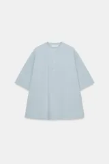 Camisa de manga corta y corte evasé confeccionada en hilatura con mezcla de algodón. Presenta cuello redondo mao y cierre frontal parcial con botones.