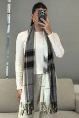 Bufanda rectangular de tejido suave con diseño de cuadros escoceses en tonos mostaza, blanco y gris, terminada con flecos en los extremos.