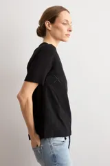 Remera negra de manga corta con panel frontal de tela broderie con diseño geométrico de rombos y espalda lisa.