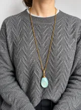 Collar con cadena dorada de eslabones y dije de resina en forma de gota de color celeste con efecto marmolado.