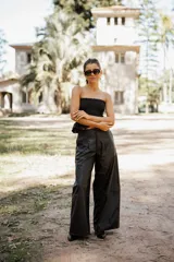 Pantalón de tiro alto confeccionado en cuero sintético, de corte amplio y pierna ancha con costura horizontal a media altura.