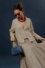 Chaqueta de lino color beige, de calce relajado, con escote en V, cierre frontal con botones y bolsillos frontales aplicados.