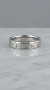 Anillo de acero inoxidable con diseño grabado de guarda griega en toda su superficie.