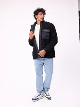 Campera reversible de sherpa y nylon, color negro, con cierre frontal, cuello alto y bolsillos frontales con solapa.