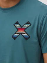 Remera de algodón orgánico color blanco, con corte regular fit y detalle de bordado en forma de X con diseño geométrico multicolor en el pecho.