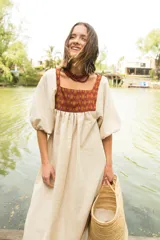 Túnica de lino color crudo con corte holgado y mangas abullonadas con elástico. Presenta una pechera frontal y trasera con estampado étnico en tonos terracota y amarillo.