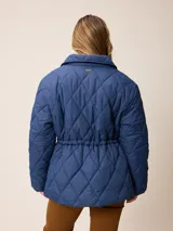 Campera acolchada de diseño matelassé con patrón de rombos, color bordó. Presenta cuello camisero, cierre frontal con cremallera metálica, cintura entallada con elástico y bolsillos laterales. Incluye un pequeño bordado distintivo en el pecho.