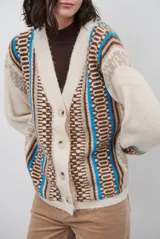 Cardigan de punto con escote en V y cierre frontal de botones. Presenta un diseño estampado con patrones geométricos en tonos beige, marrón y detalles en azul vibrante.