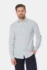 Camisa de manga larga, corte slim fit, color celeste con finas rayas verticales blancas. Presenta cuello camisero y un pequeño logo bordado en el pecho.