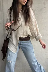 Camisa beige de rayas verticales, de calce relajado y tejido liviano, con mangas largas y cuello camisero.