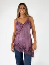 Top de viscosa color lila con efecto acid wash, tirantes finos y detalles de encaje floral en el escote y en el ruedo asimétrico.