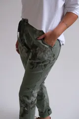 Pantalón de corte recto y tiro medio con estampado floral en tonos verdes. Presenta cintura elástica con cordón de ajuste, bolsillos laterales y dobladillo en los tobillos.