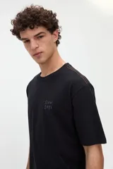 Remera de manga corta color beige, confeccionada en jersey de algodón con textura suave y calce relaxed. Presenta costuras a contratono en la espalda y un diseño estampado en la parte posterior con ilustraciones de estilo lineal y frases manuscritas.