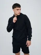 Campera deportiva Umbro modelo Terrace, color negro, con capucha y cierre frontal completo. Cuenta con bolsillos tipo canguro y detalles de la marca en las mangas.