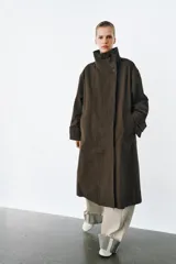 Trench oversize de Zara Woman Collection, confeccionado en mezcla de algodón con estampado de cuadros pequeños. Presenta cuello alto, cierre frontal con botones, mangas largas con trabillas ajustables y bolsillos laterales.