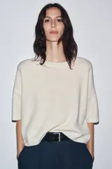 Jersey de punto color crema, confeccionado en 100% lana, con cuello redondo y mangas cortas anchas, de calce amplio.