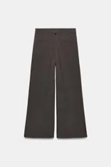 Pantalón de tiro medio con corte wide leg, presenta pliegues frontales, bolsillos laterales y trabilla con botón en la espalda. Cierre frontal con cremallera y botón.