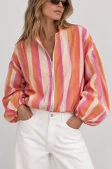 Campera bomber de diseño ligero, con estampado de rayas verticales multicolor en tonos rosado, naranja, fucsia y beige. Presenta cuello alto, cierre frontal completo y mangas largas abullonadas con puños elastizados.