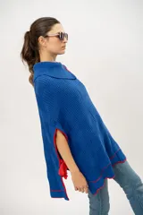 Capa tipo poncho tejido de punto color azul con detalles en rojo.