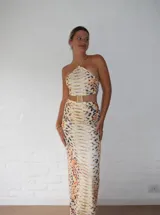 Vestido midi con estampado de piel de serpiente en tonos beige y marrón. Diseño con top halter y falda tubo con abertura lateral.