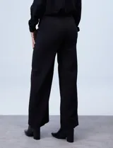 Pantalón de vestir de corte wide leg color negro, con cintura alta, detalle de botones decorativos en la parte frontal y bolsillos laterales.
