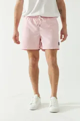 Short de baño liso color rosa con cintura elástica y cordón ajustable. Tiene dos bolsillos laterales, un bolsillo trasero y logo bordado.