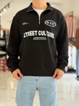 Buzo negro con medio cierre frontal y cuello alto, de manga larga y diseño holgado, con estampa en el pecho con las inscripciones "STREET CULTURE" y "TOP STYLE".