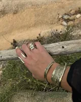 Brazalete rígido de diseño artesanal con textura irregular y acabado metálico, elaborado en bronce macizo.