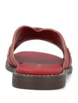Sandalias planas de cuero rojo con tiras cruzadas y tachas metálicas doradas.