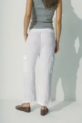 Pantalón de lino blanco, de corte recto y tiro alto, con bolsillos laterales y traseros.