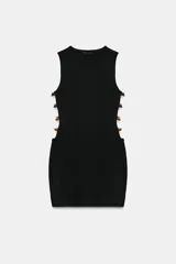 Vestido corto de punto color negro, con cuello redondo y diseño sin mangas. Presenta aberturas laterales decoradas con abalorios en tonos tierra.