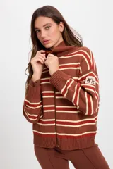 Campera de punto holgada con cuello tipo chomba y cierre frontal oculto. Presenta un diseño de rayas horizontales en tonos marrón, rojo y crema, con puños y ruedo acanalados. Incluye un parche bordado en la manga izquierda.