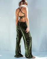 Enterito de terciopelo negro con diseño de pierna ancha y bolsillos laterales tipo cargo. Presenta espalda descubierta con tiras ajustables y bordado decorativo en la parte trasera.