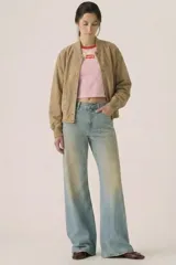 Campera tipo bomber cropped de gamuza sintética color beige, con cuello, puños y ruedo de rib elástico. Cuenta con bolsillos laterales ribeteados y cierre frontal con botones a presión metálicos.