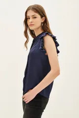 Camisa negra de poliéster con corte recto, cuello mao y volados en las mangas.