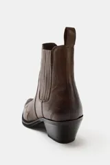 Botín cowboy de piel color marrón con detalles bordados en el cuerpo, elástico lateral, tirador trasero y tacón ancho en bloque con acabado en punta.