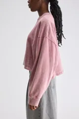 Remera oversize de manga larga y largo cropped color blanco, confeccionada en jersey de algodón, con cuello redondo y terminaciones desgastadas.