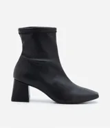 Bota de caña corta color negro, confeccionada en material sintético, con taco mediano bloque y puntera cuadrada.