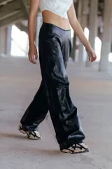 Pantalón de ecocuero negro, corte ancho, con bolsillos laterales y traseros, y cintura elástica en la parte posterior.