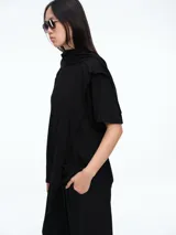Remera de manga corta con diseño de buzo integrado en la parte superior, creando un efecto visual de prenda superpuesta. Confeccionada en algodón, presenta un corte relajado y cuello redondo.