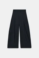Pantalón de tiro medio con diseño de raya diplomática, corte wide leg y detalle de pinzas en el delantero. Cuenta con cintura con trabillas, bolsillos laterales y cierre frontal con cremallera, botón y ganchos metálicos.