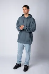 Buzo canguro oversize de tela friza, color negro, con capucha, cordones ajustables con logo y bolsillo frontal tipo canguro.