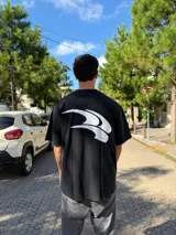 Remera negra de corte oversize con estampado gráfico blanco en la espalda.