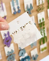 Aros tipo caravanas con diseño floral compuesto por pétalos superpuestos en color blanco traslúcido.