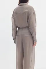 Camisa gris de efecto sedoso, manga larga, con cuello clásico, cierre frontal con botones y bolsillos delanteros con solapa y bordado.