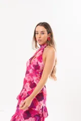 Vestido largo fucsia con estampado abstracto, cuello halter con abertura en forma de lágrima y volados en la falda.