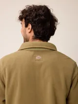 Sobrecamisa de polar azul marino con cierre frontal de botones a presión. Presenta bolsillos frontales con solapa, uno de ellos con cierre de cremallera adicional y detalles en contraste de material técnico.