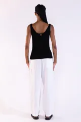 Musculosa de punto canalé color negro, tejida con hilos metálicos de lurex que aportan un brillo sutil, con escote bote y tirantes anchos.