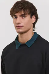 Buzo de algodón rústico color negro con cuello redondo y detalle de cuello tipo polo en color verde oscuro debajo. Presenta puños y ruedo acanalados, con un diseño de calce clásico.