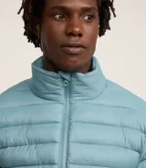 Campera puffer ultraligera de cuello alto con cierre frontal por cremallera y bolsillos laterales. Diseño acolchado con acabado liso.